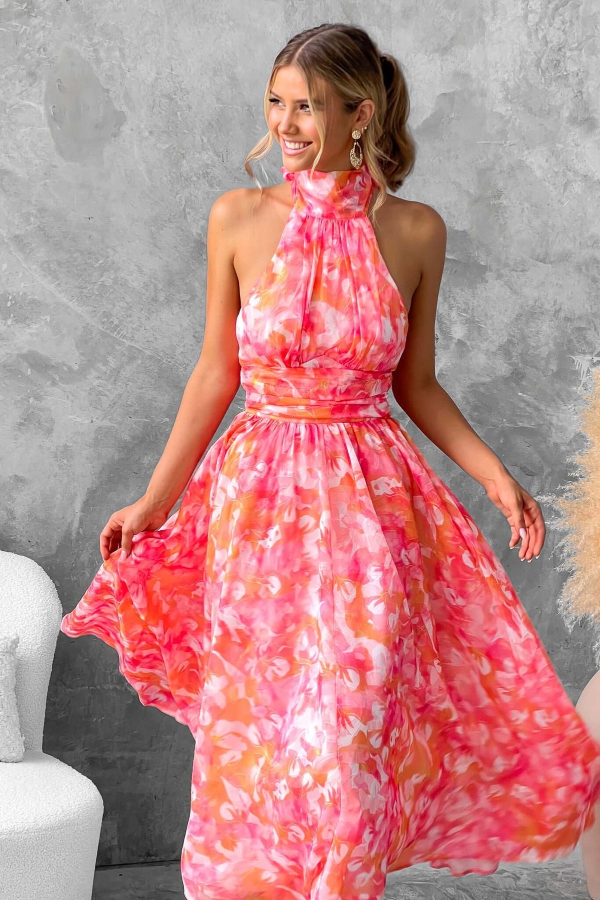 Model wearing a vibrant floral Little Things Maxi Dress with a high tie neckline and flowing skirt.