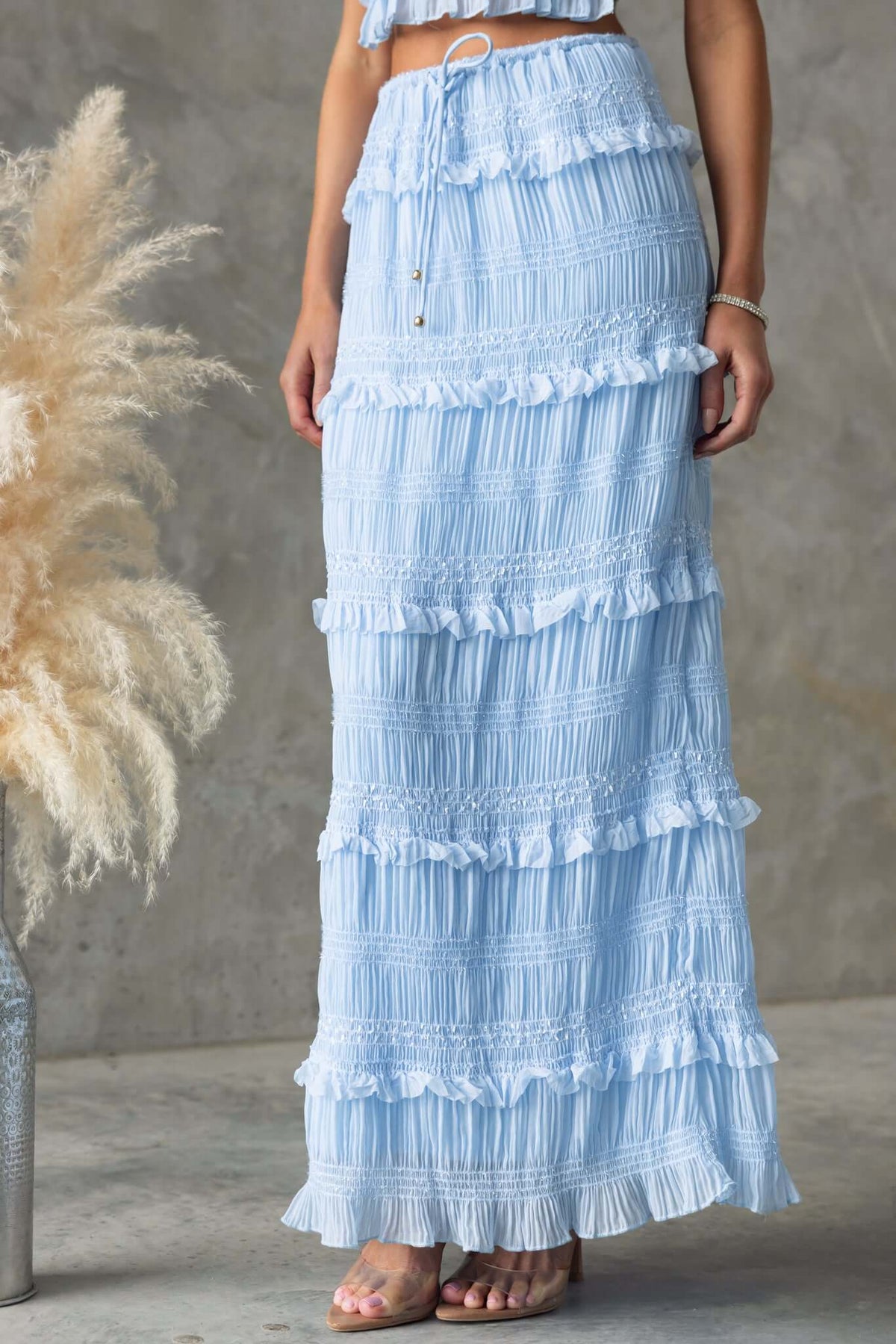 Lolana Maxi Skirt in light blue with ruffles and a mid-high waist, featuring an elastic waistband and drawstring.