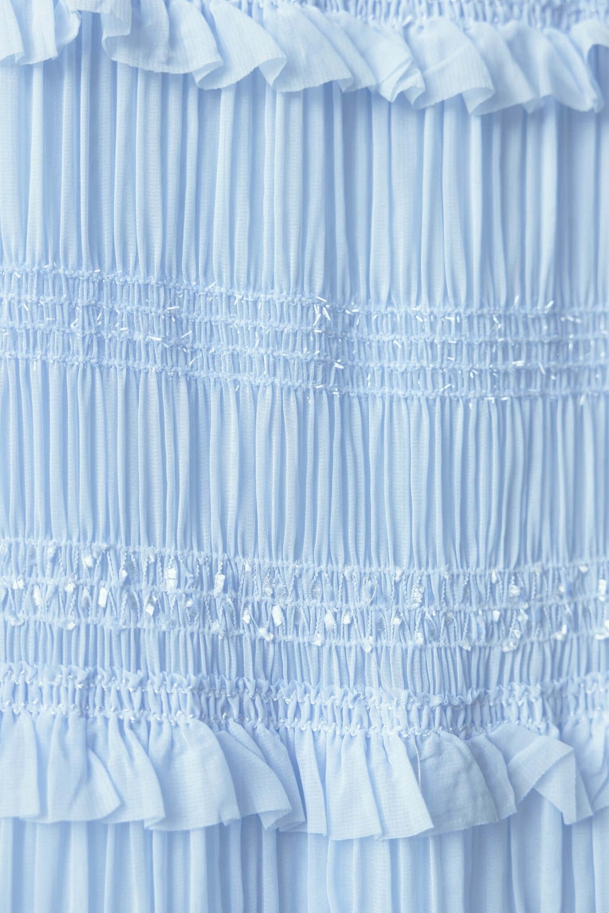 Close-up of light blue textured fabric with ruffles and metallic thread, showcasing the elegant design of a maxi skirt.
