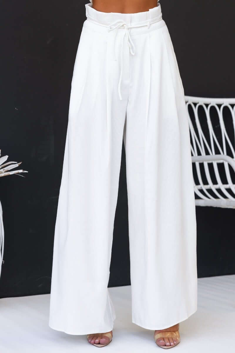 White paperbag waist pants with removable fabric tie and wide legs, perfect for a stylish and trendy look.