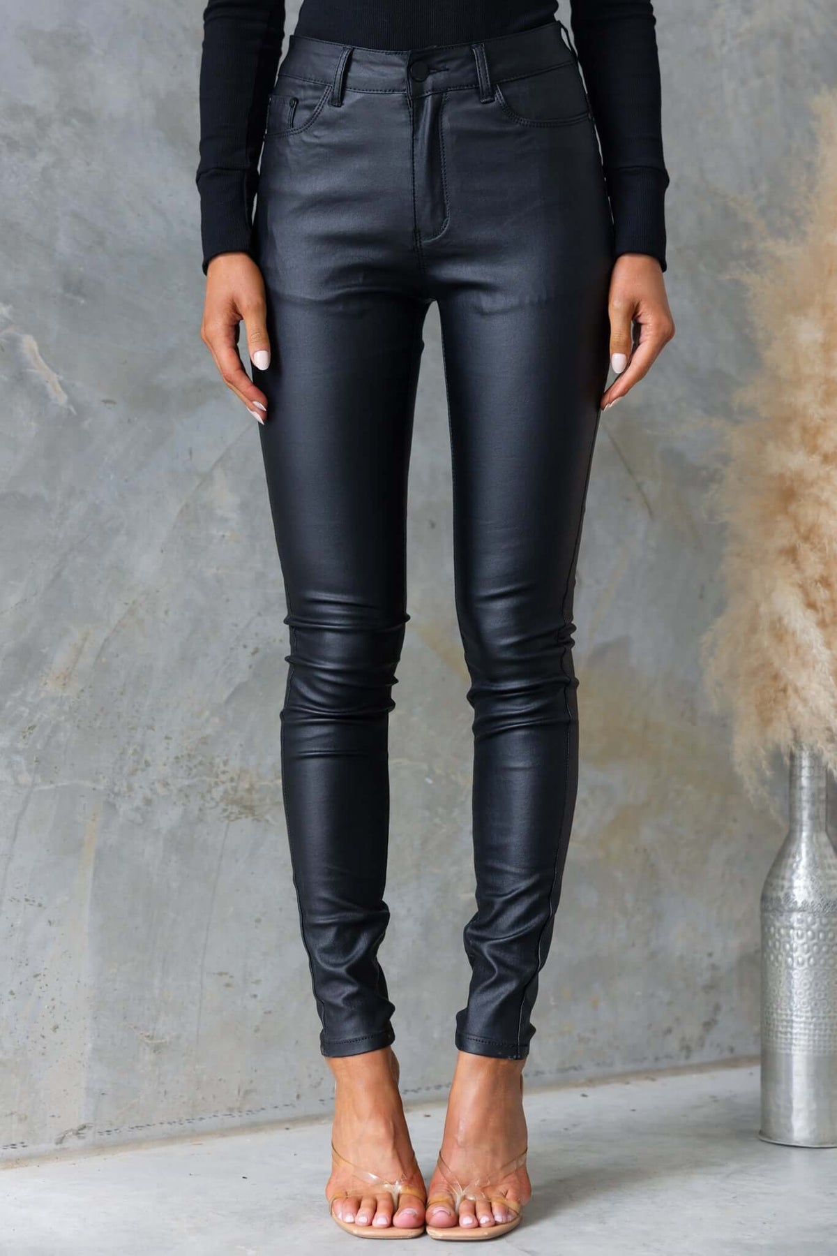 Luscious black faux leather pants with a mid to high waist fit, showcasing a firm stretch and a stylish silhouette.