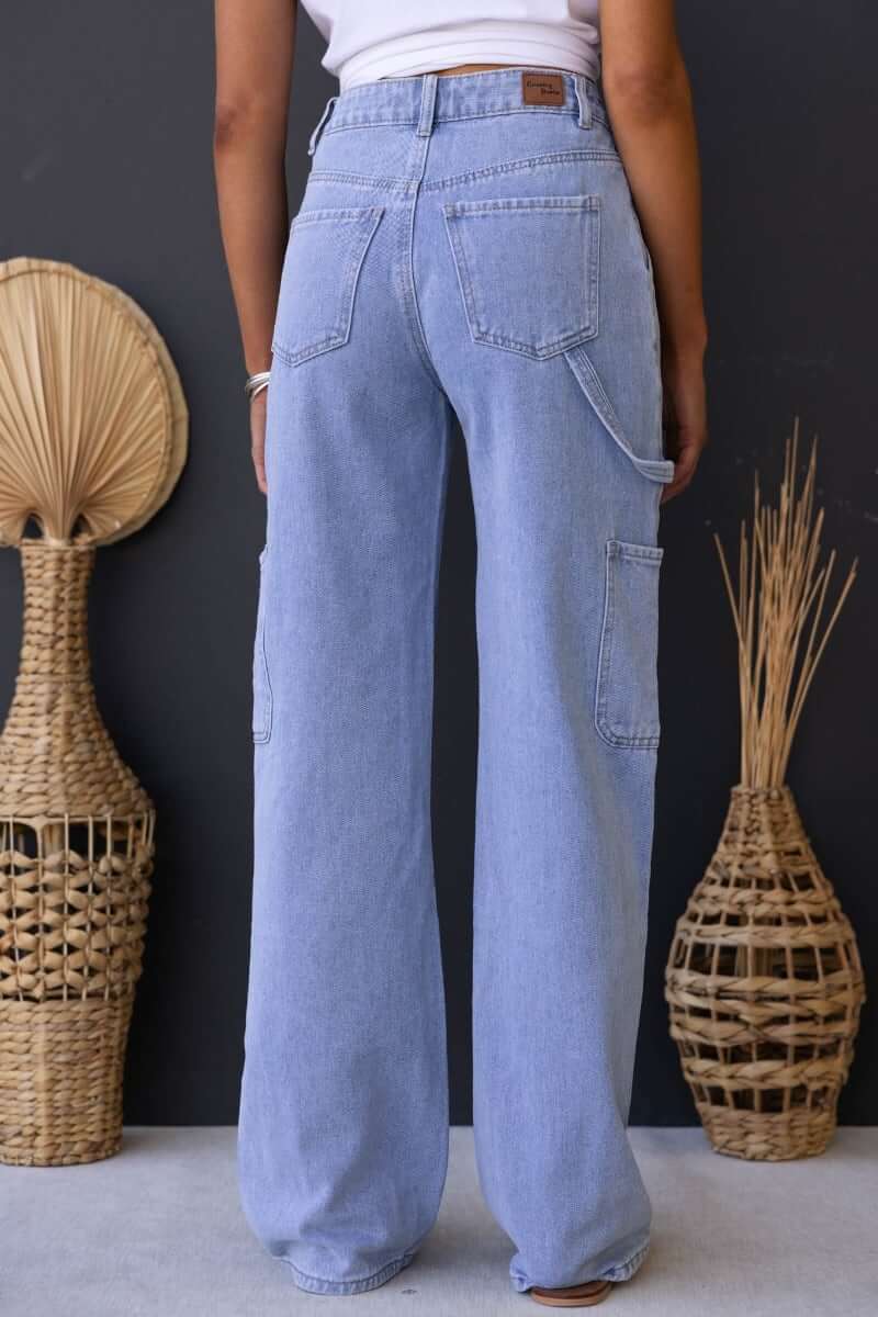 Back view of a woman wearing light blue cargo style Madrid jeans with pockets, showcasing a mid-high waist fit.