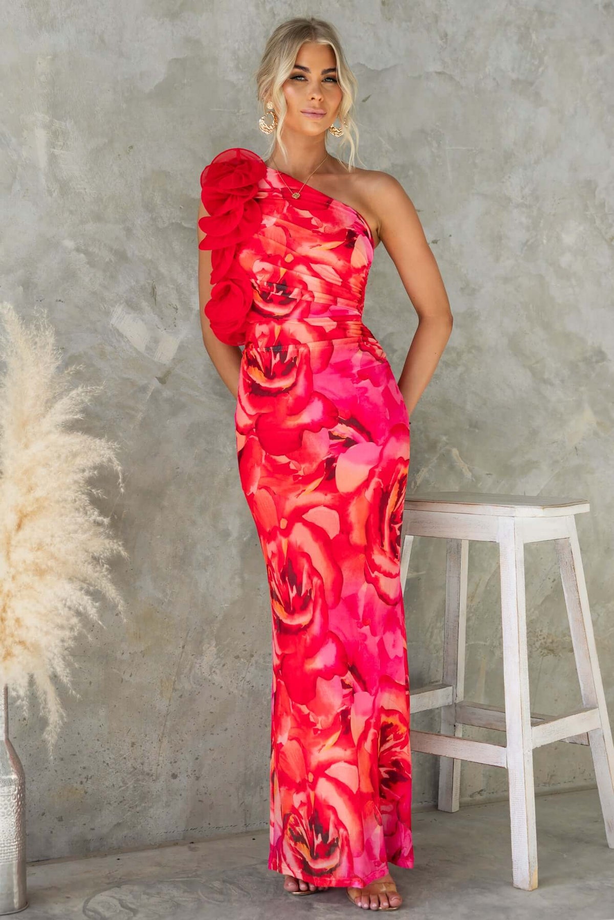 Model wearing Meriden Maxi Dress with one-shoulder neckline and vibrant floral print, styled against a neutral background.