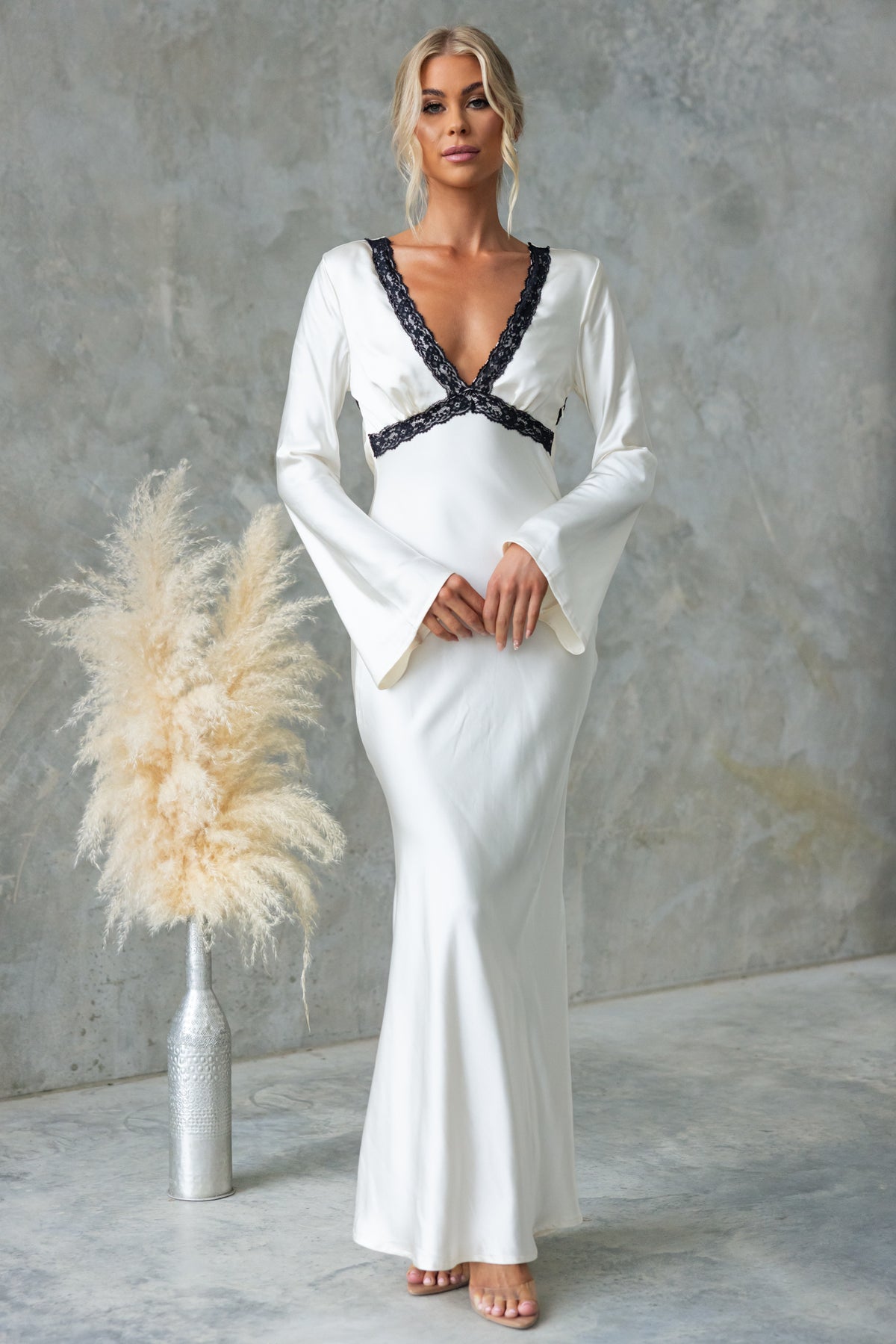 Elegant Nicholie Maxi Dress in white with lace detail, flared sleeves, and a fitted silhouette showcased by model.