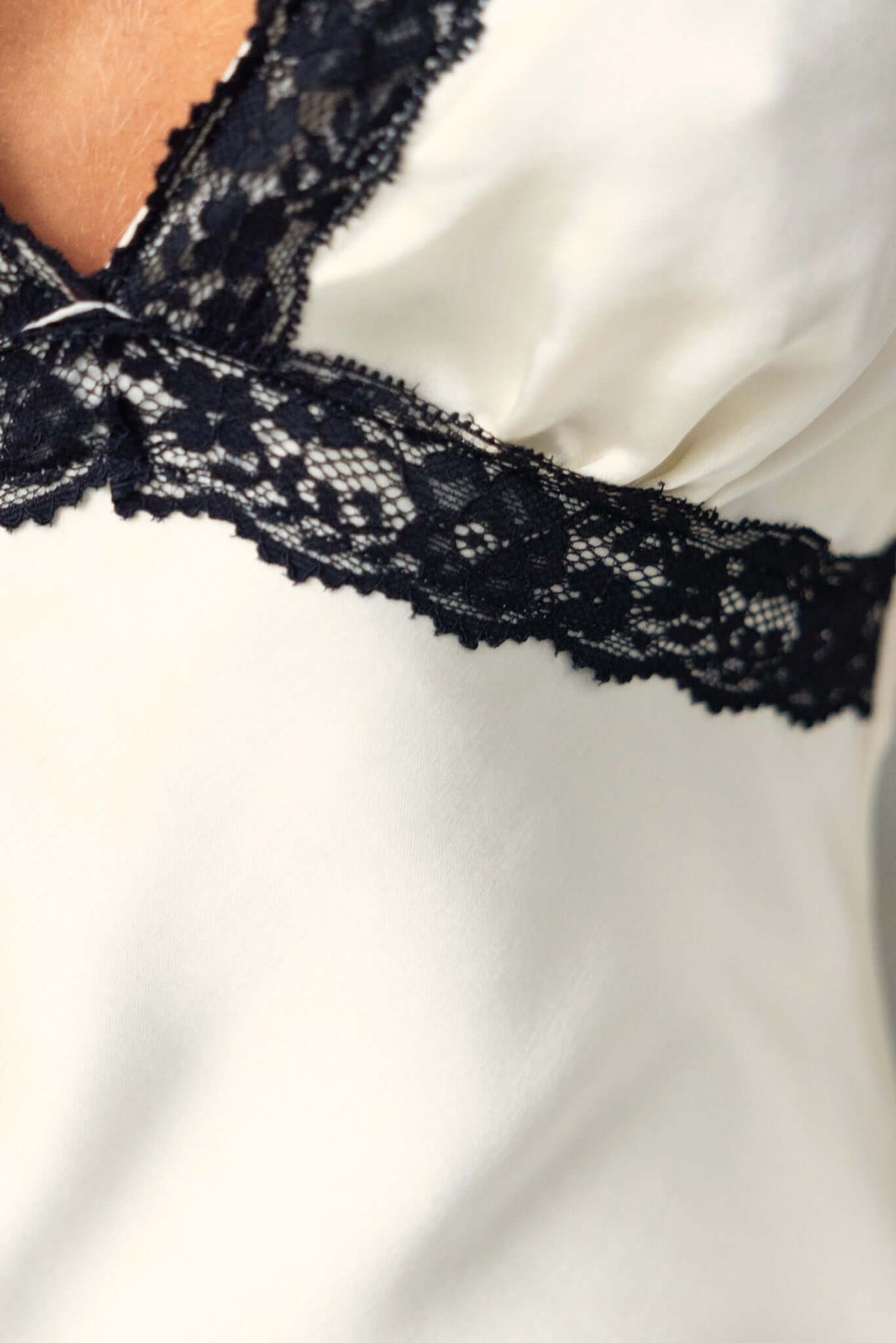 Close-up of Nicholie Maxi Dress showing black lace detail on cream fabric, emphasizing elegant design features.