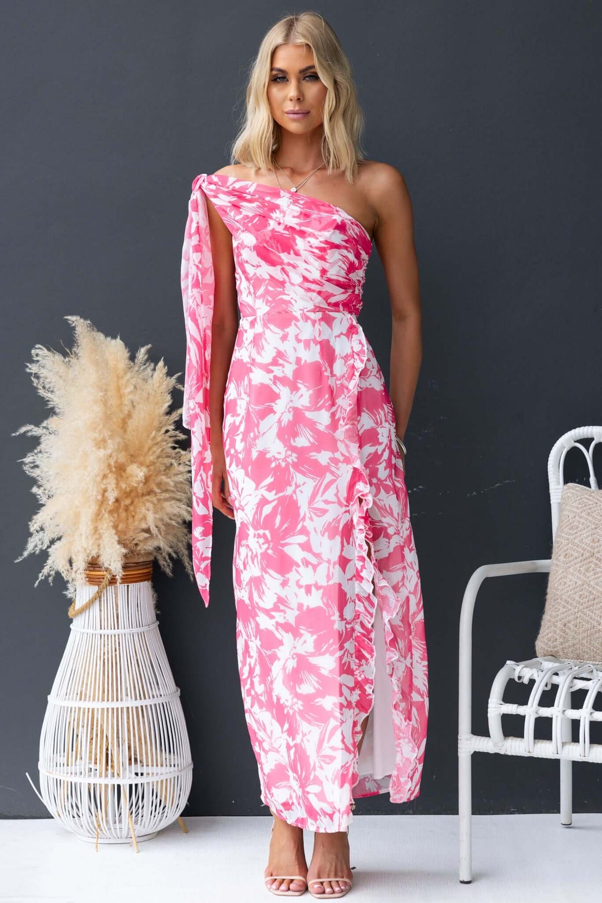 Model wearing a pink floral Nurture Maxi Dress, featuring a strapless design and side split, styled elegantly.
