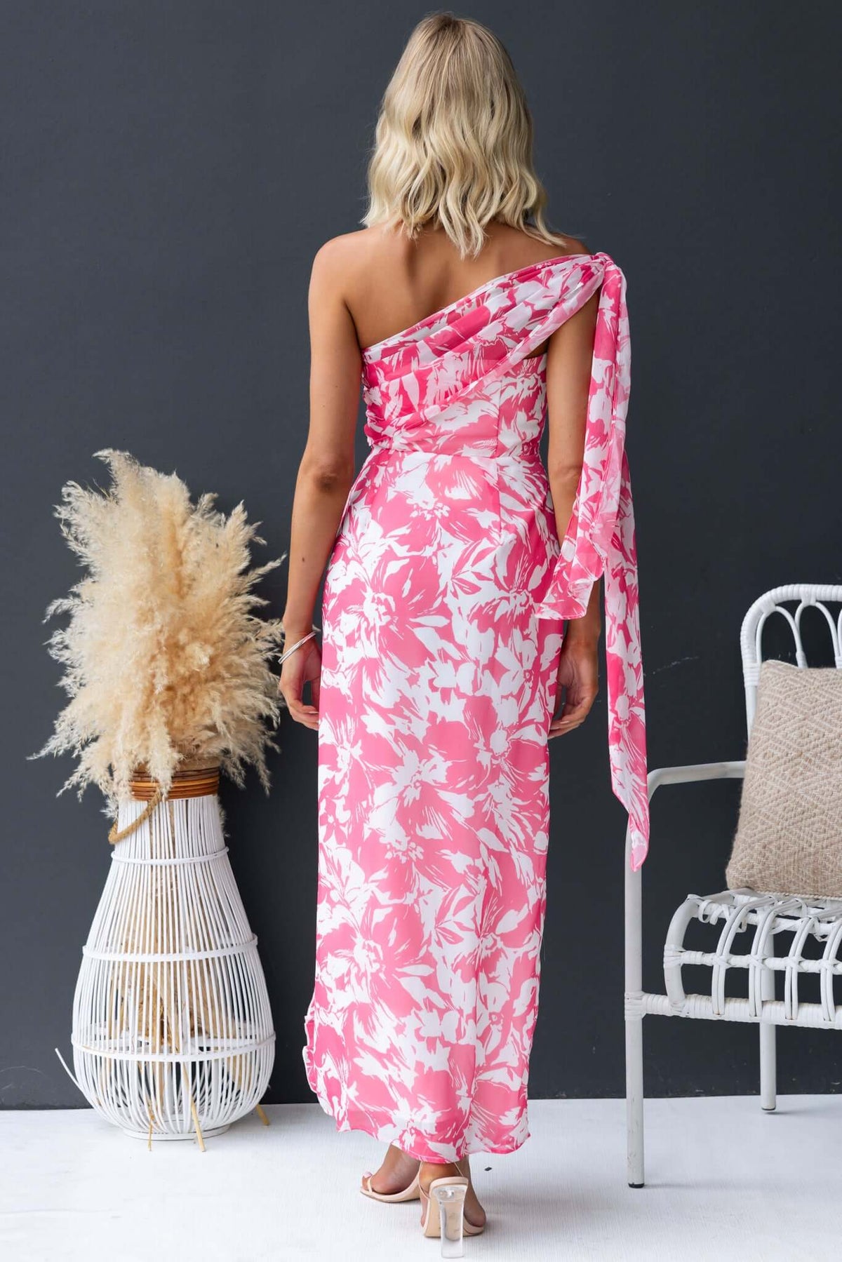 Back view of a strapless Nurture Maxi Dress in vibrant pink floral design, featuring an elegant tie detail and flowing silhouette.