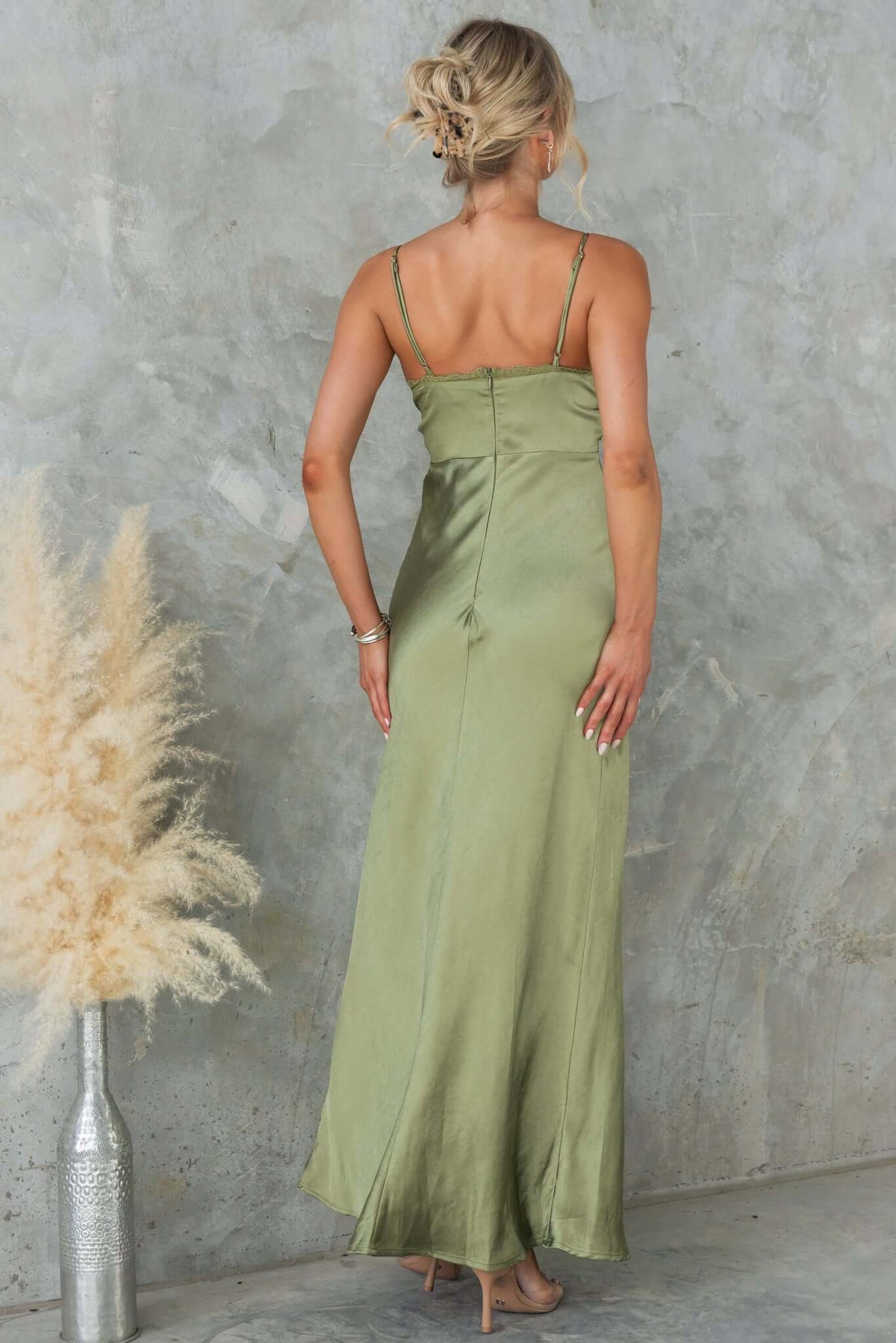 Back view of a model wearing an olive green Obsidian Maxi Dress with adjustable straps and a lace panel design.