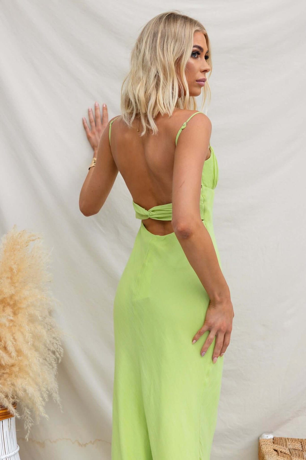Back view of a woman in a green Orinthia maxi dress featuring adjustable straps and a cut-out design.
