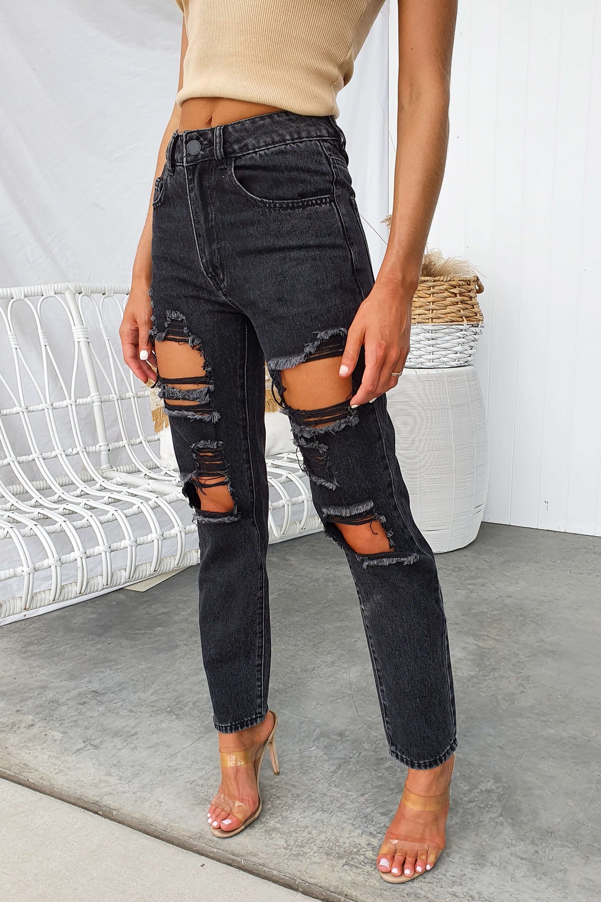 Distressed black wash mom jeans with ripped details, styled for a trendy casual look.
