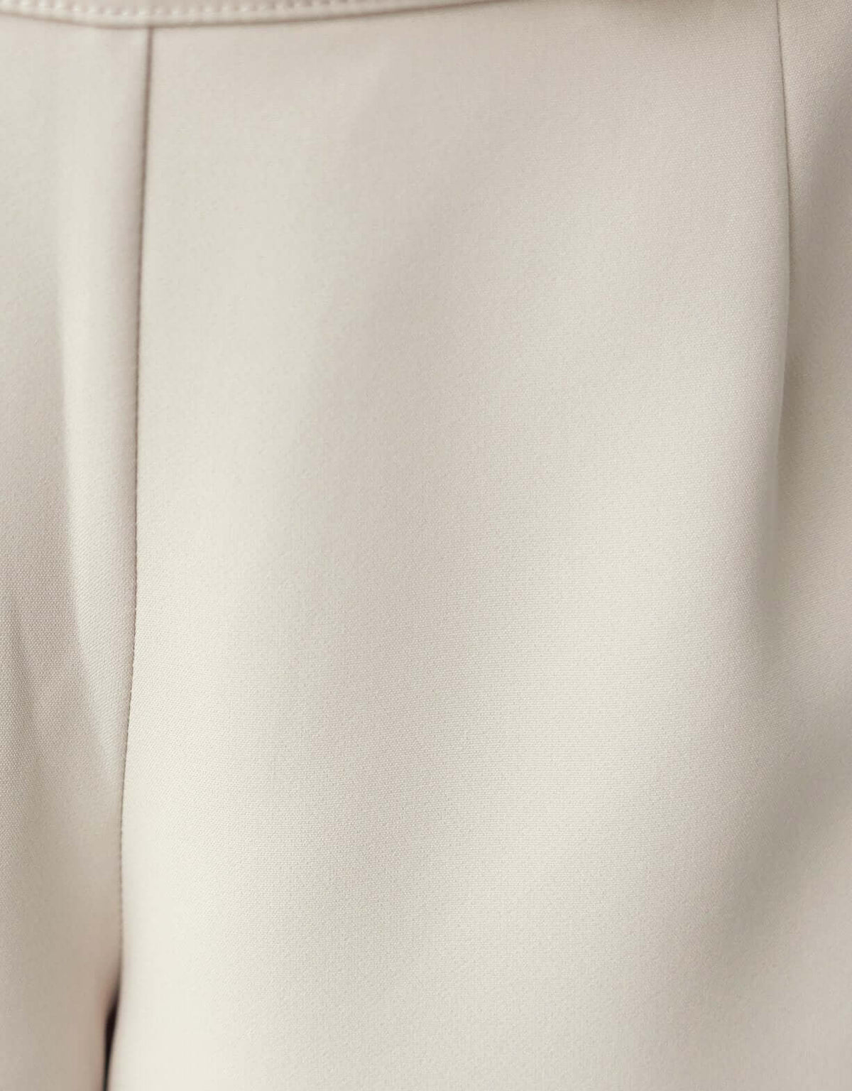 Close-up of Roan Pants fabric in a light beige color, showcasing the smooth texture and mid-high waist design.