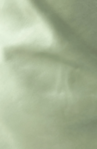 Close-up of soft, light green fabric with a smooth texture, ideal for fashion or interior design.