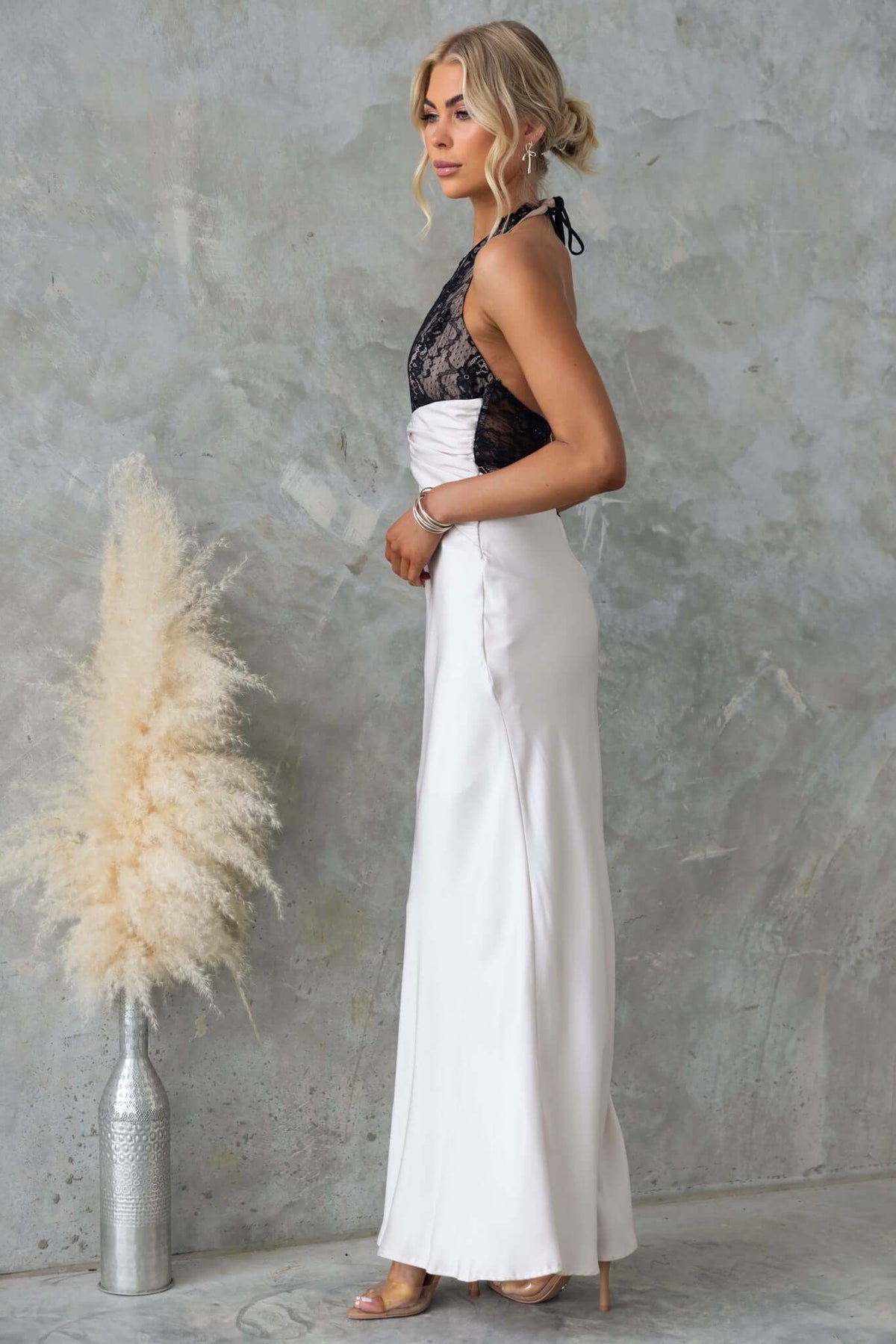 Elegant Sonrisa Maxi Dress featuring a lace bust and satin finish, showcased on model against textured backdrop.