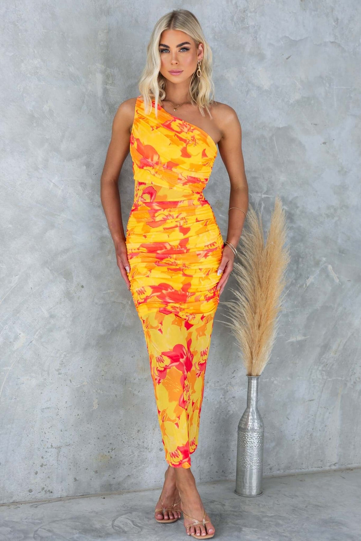Sundara Maxi Dress featuring a one-shoulder neckline and vibrant floral print, styled with a modern touch.