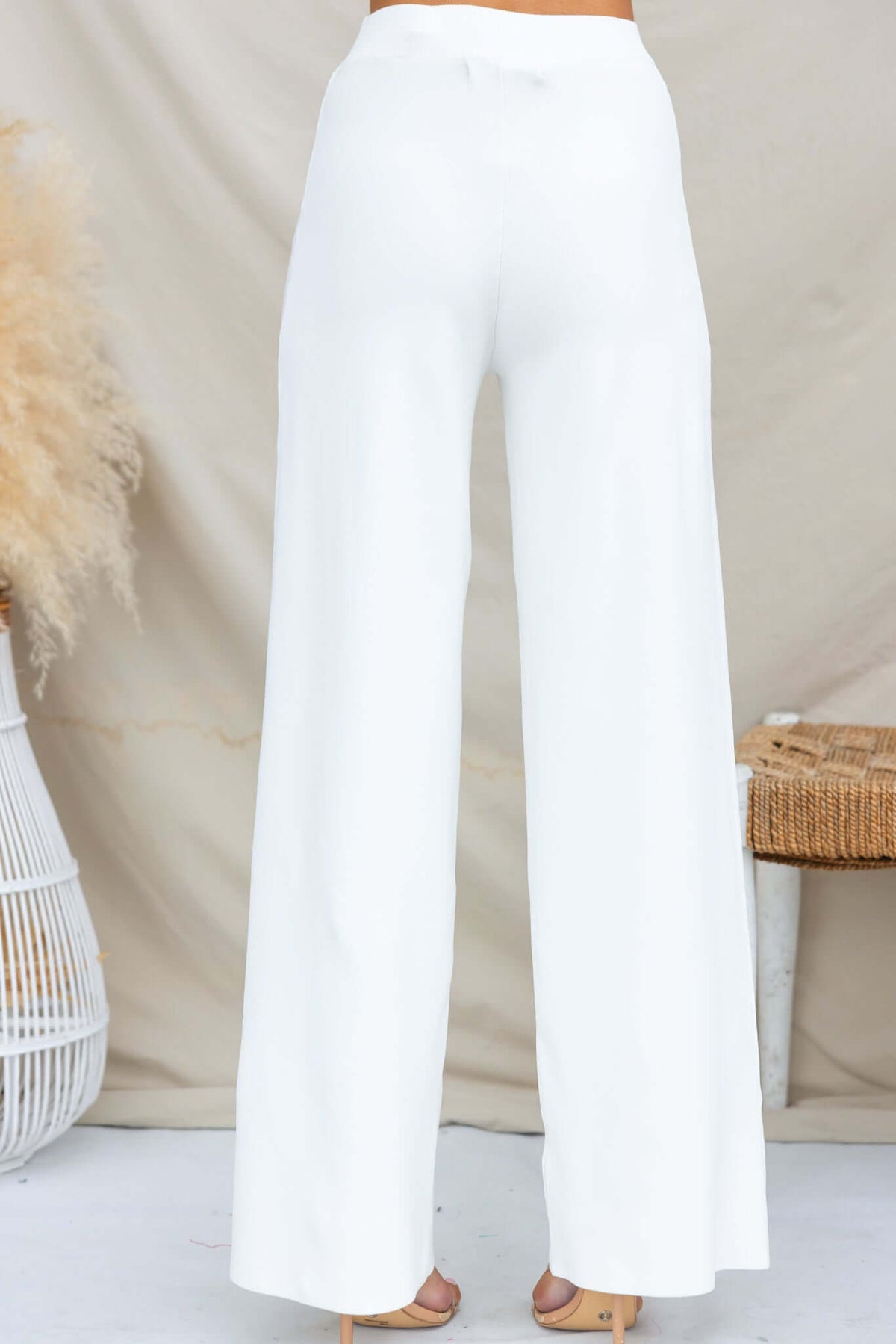 Back view of Tammie Pants in white, featuring a mid-high waist fit and wide-leg style, made from stretchy knit material.