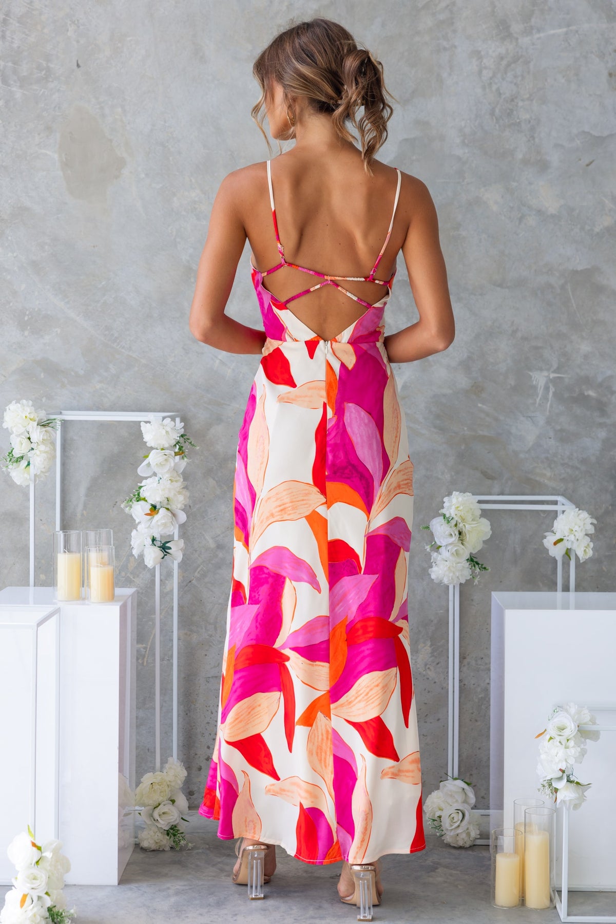 Back view of model wearing Temptress Maxi Dress with vibrant floral patterns and adjustable straps.