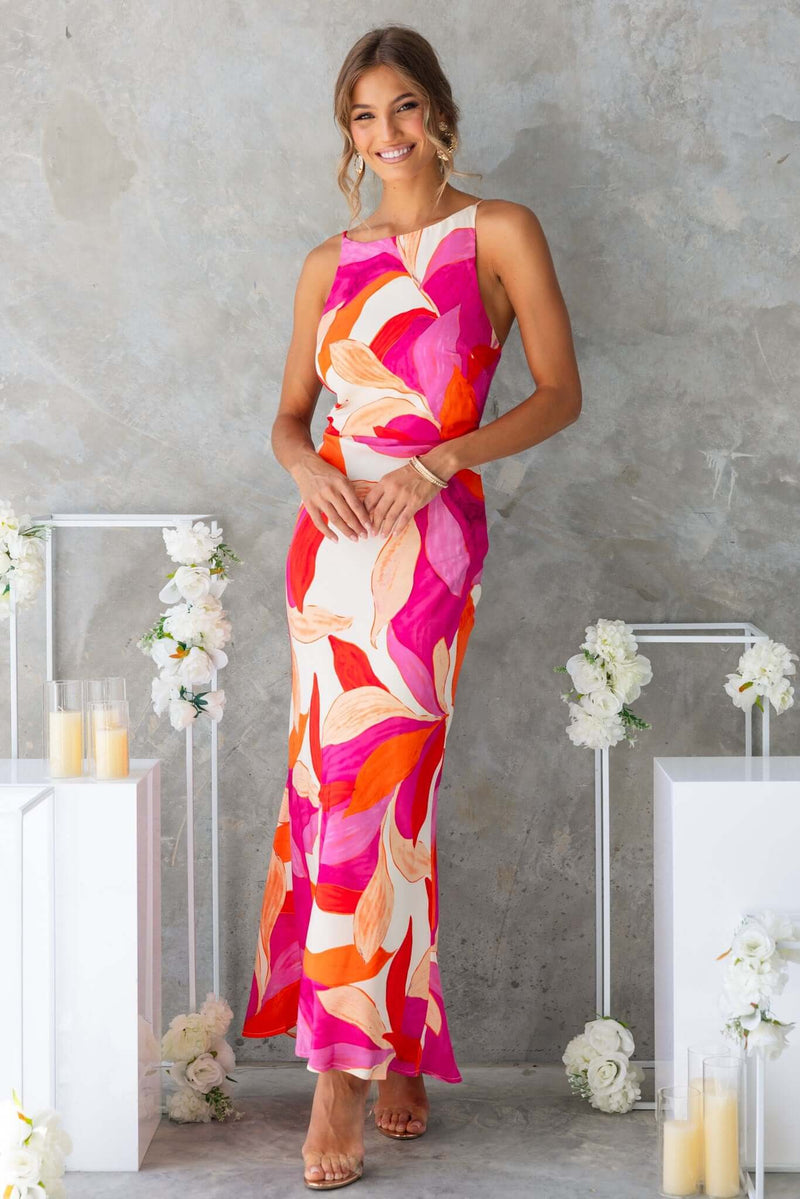 Model wearing the Temptress Maxi Dress with floral design, featuring a high neckline and adjustable straps.