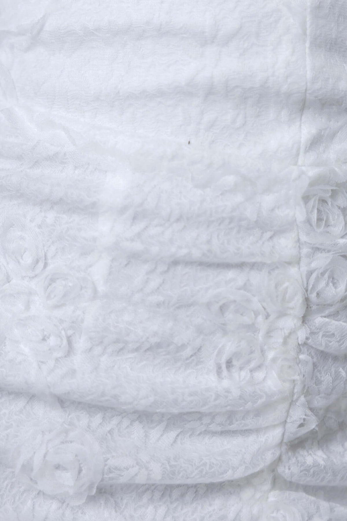 Close-up of textured fabric of the Metrick Maxi Dress, featuring intricate floral details in white.