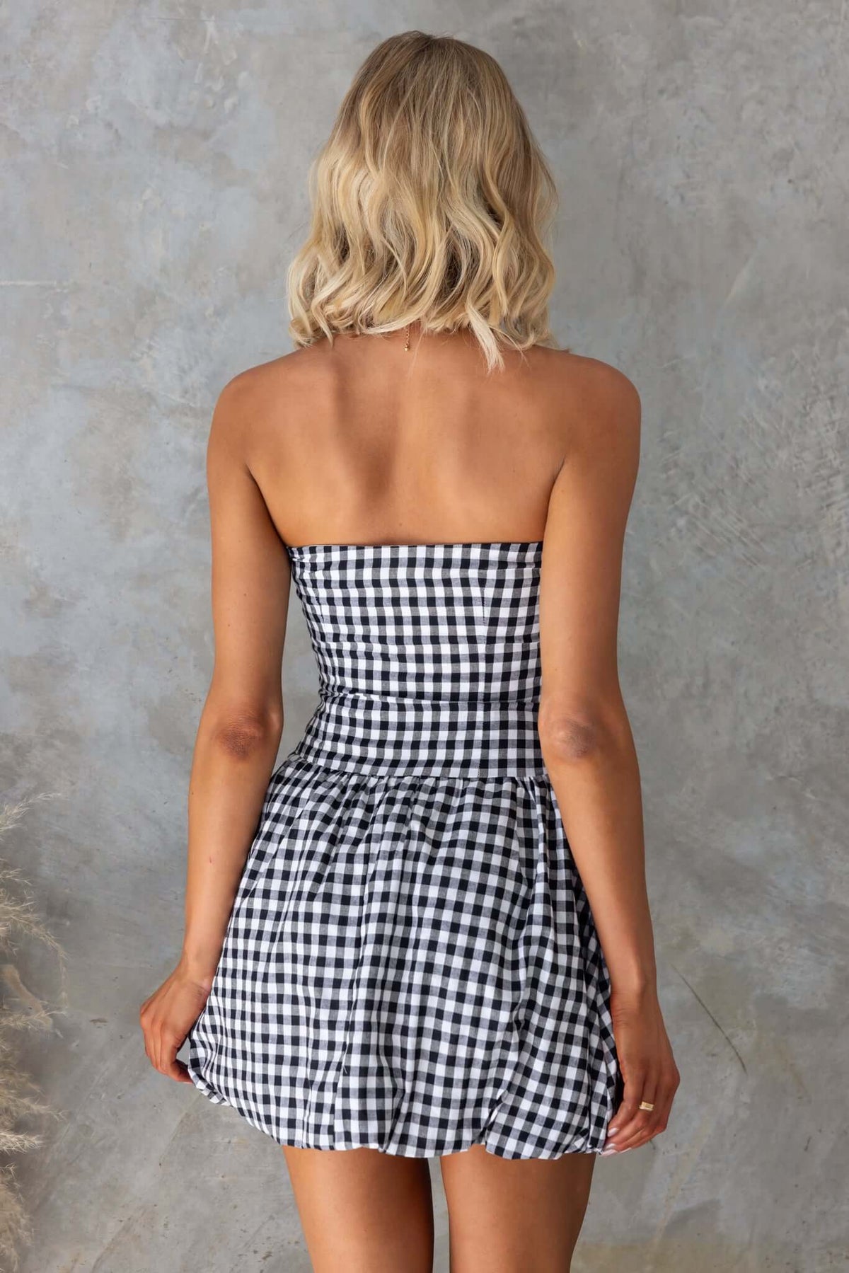 Strapless Toni Dress with a bubble hem and checkered pattern, showcased from the back.