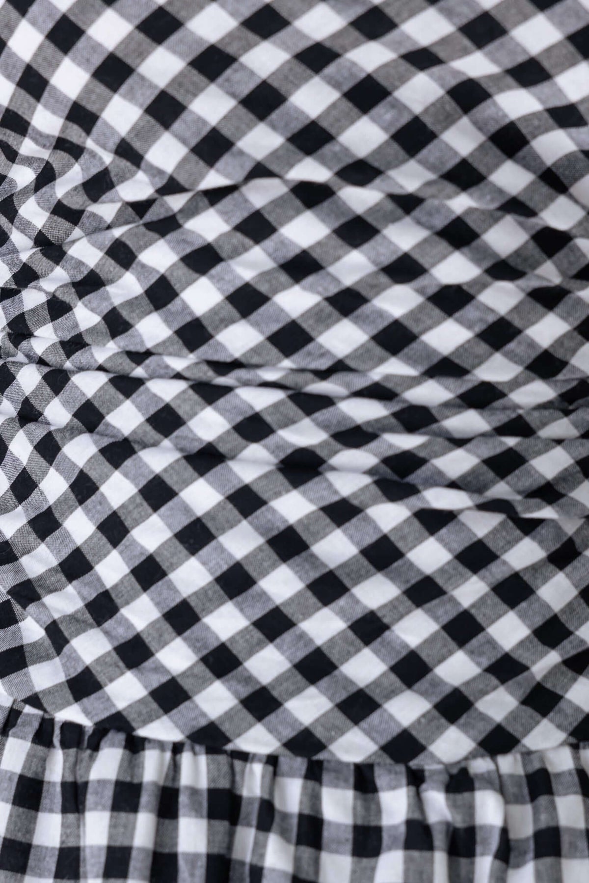 Close-up of the Toni Dress featuring a black and white gingham pattern and bubble hem detail.