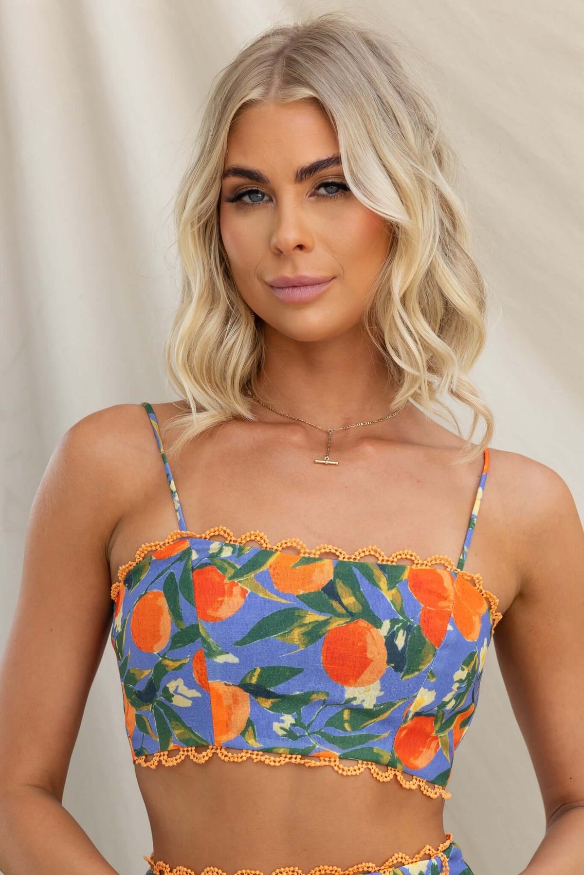 Umeeka Top with adjustable straps and tie at back, featuring vibrant orange floral pattern on a blue background.