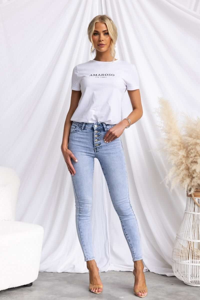 Model wearing Under Cover Jeans with button-up front and mid-high waist, paired with a white t-shirt.