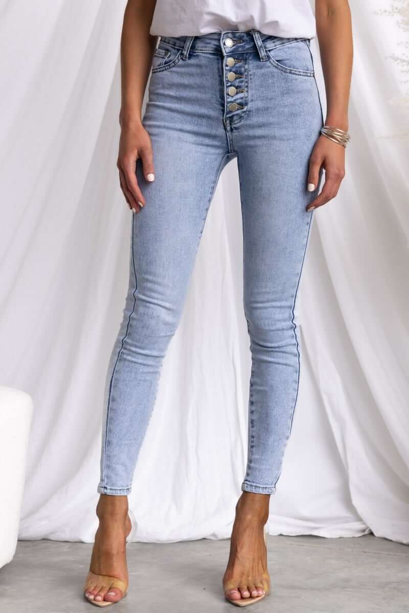 Model wearing Under Cover Jeans, light blue high-waisted denim with button-up front and skinny fit.