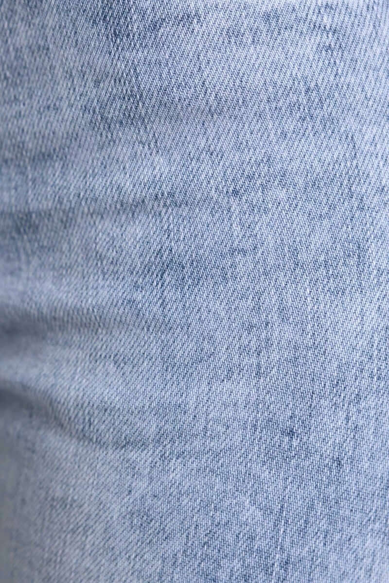 Close-up of light blue denim fabric texture of Under Cover Jeans with a smooth finish.