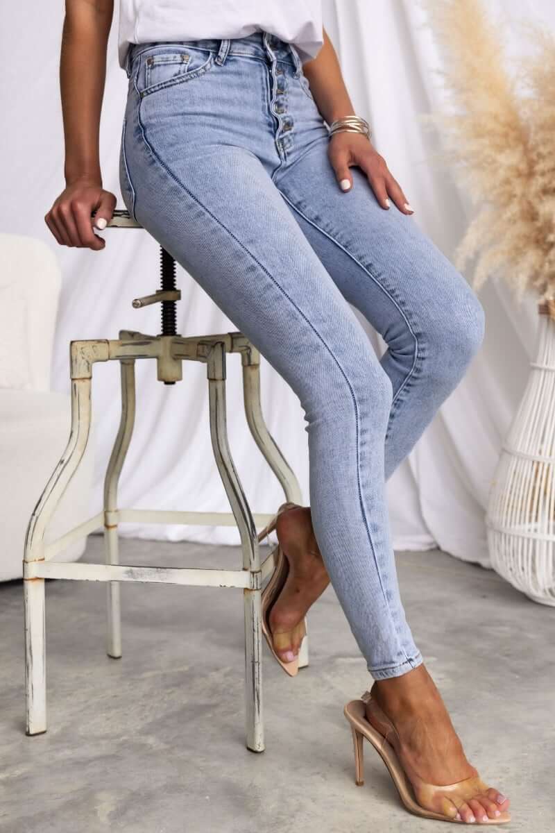Model showcasing Under Cover Jeans in light blue, skinny fit, mid-high waist, styled with transparent heels.