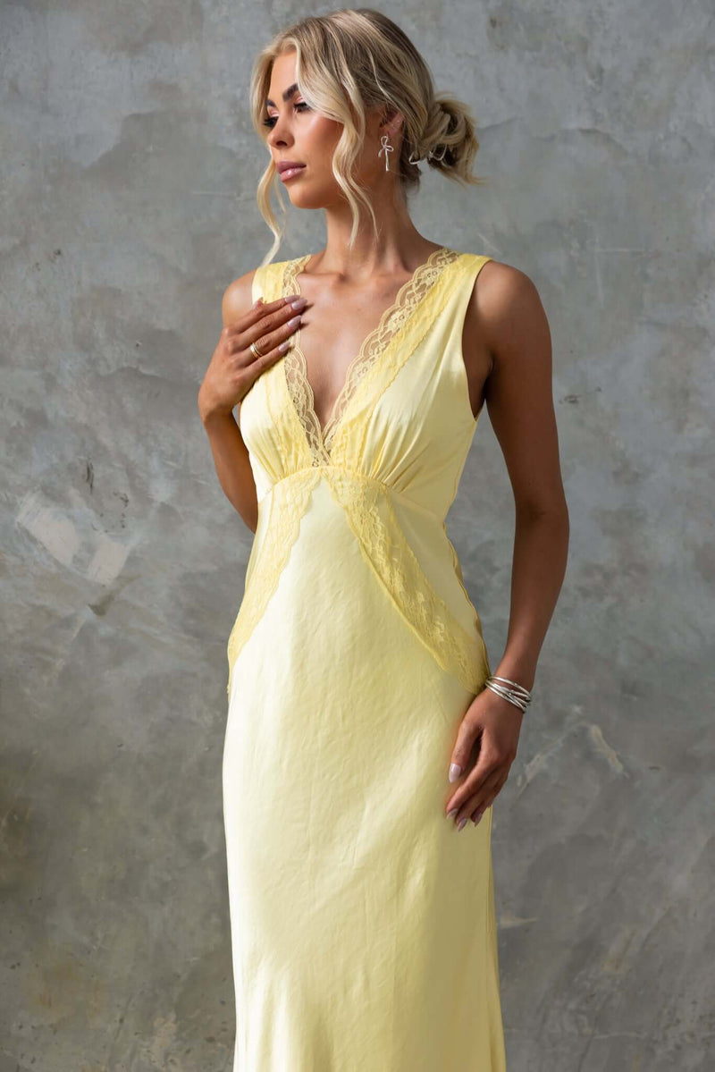 Uvira Maxi Dress in yellow satin, featuring a V-neckline and lace trim, elegantly styled with a side invisible zip.