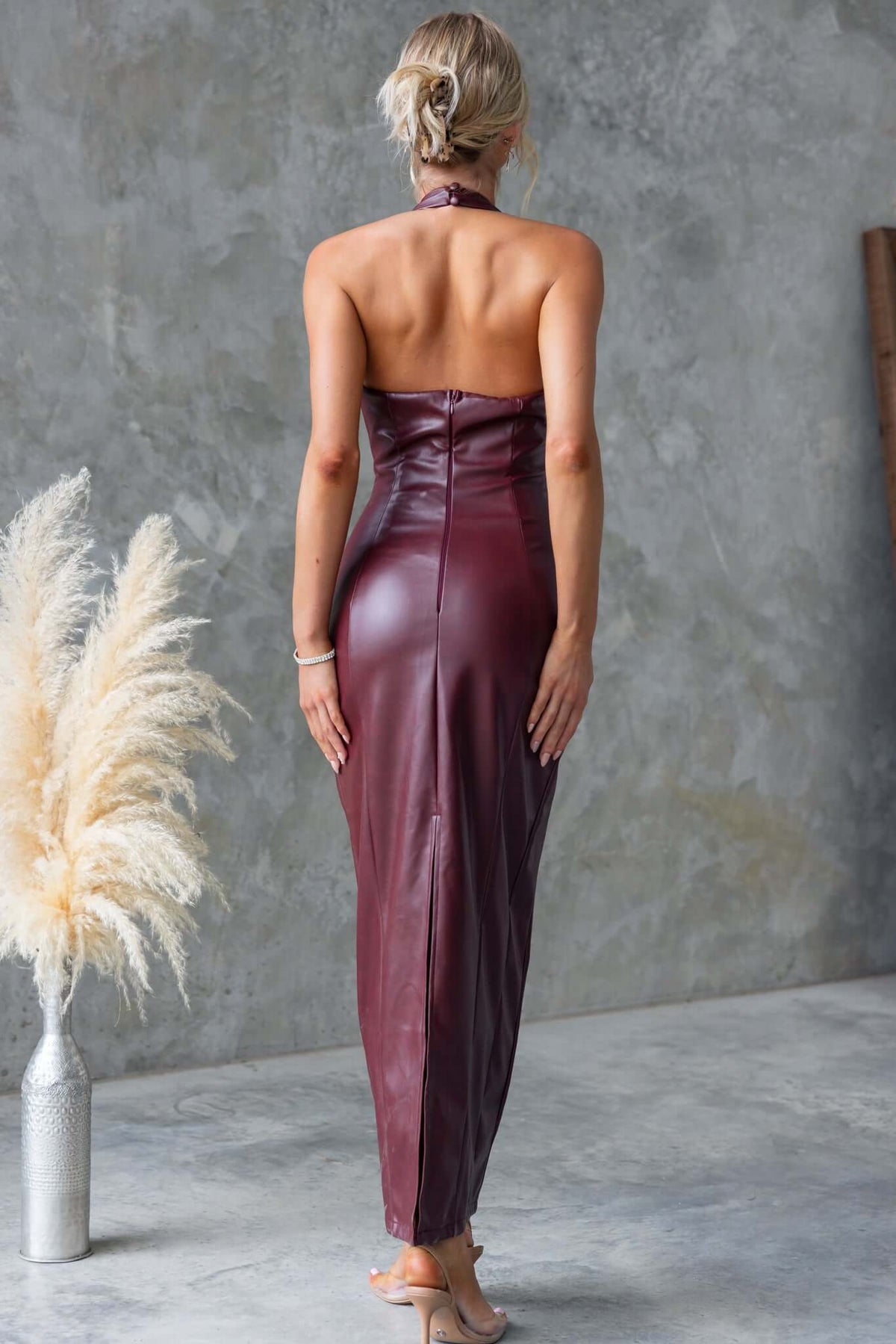 Back view of the Veridan Maxi Dress in faux leather with halter neckline and split, showcasing a sleek fit.