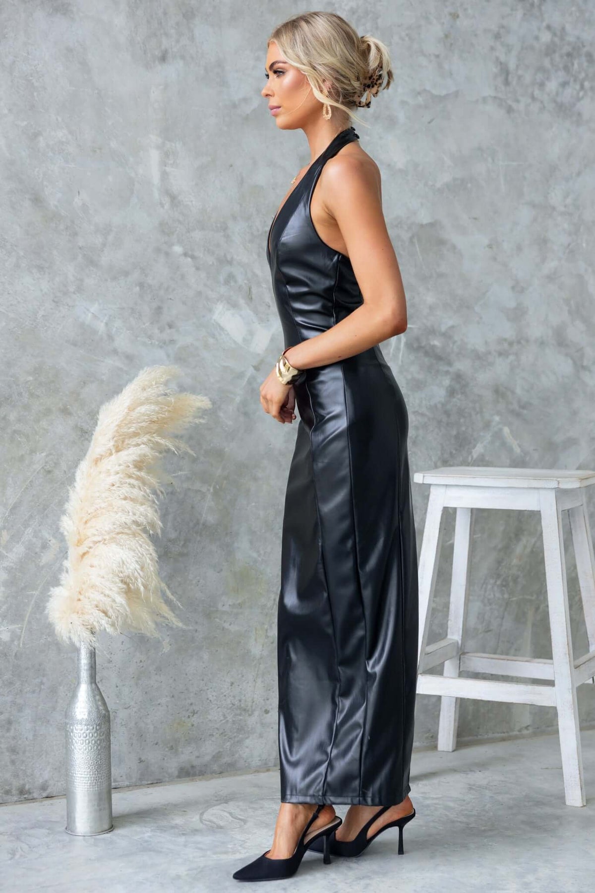Model wearing the Veridan Maxi Dress with halter neckline and faux leather material, showcasing back split and elegant fit.