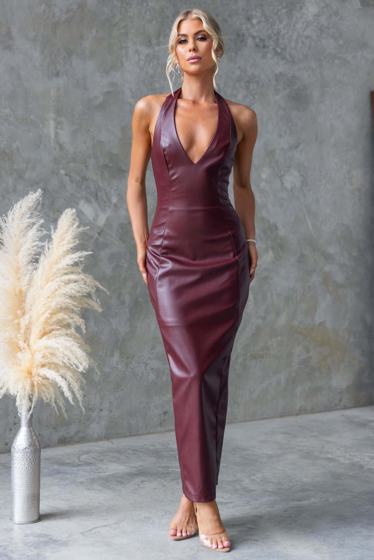 Model wearing a stylish burgundy Veridan Maxi Dress with halter neckline and faux leather material.