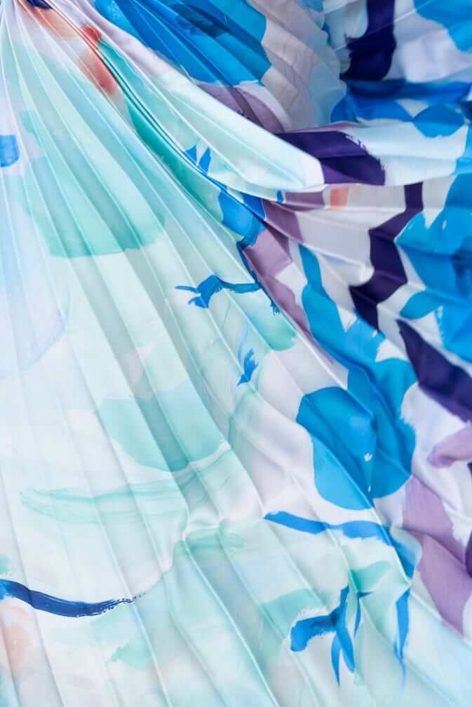 Close-up of accordion pleat fabric with a blue and purple floral pattern for the Olympia Maxi Dress.