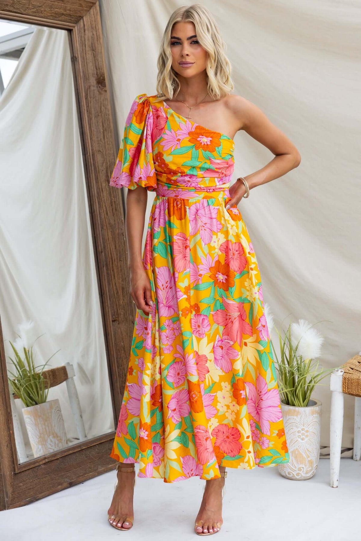 Model wearing Woran floral midi dress with one-shoulder neckline and vibrant colors in a stylish setting.