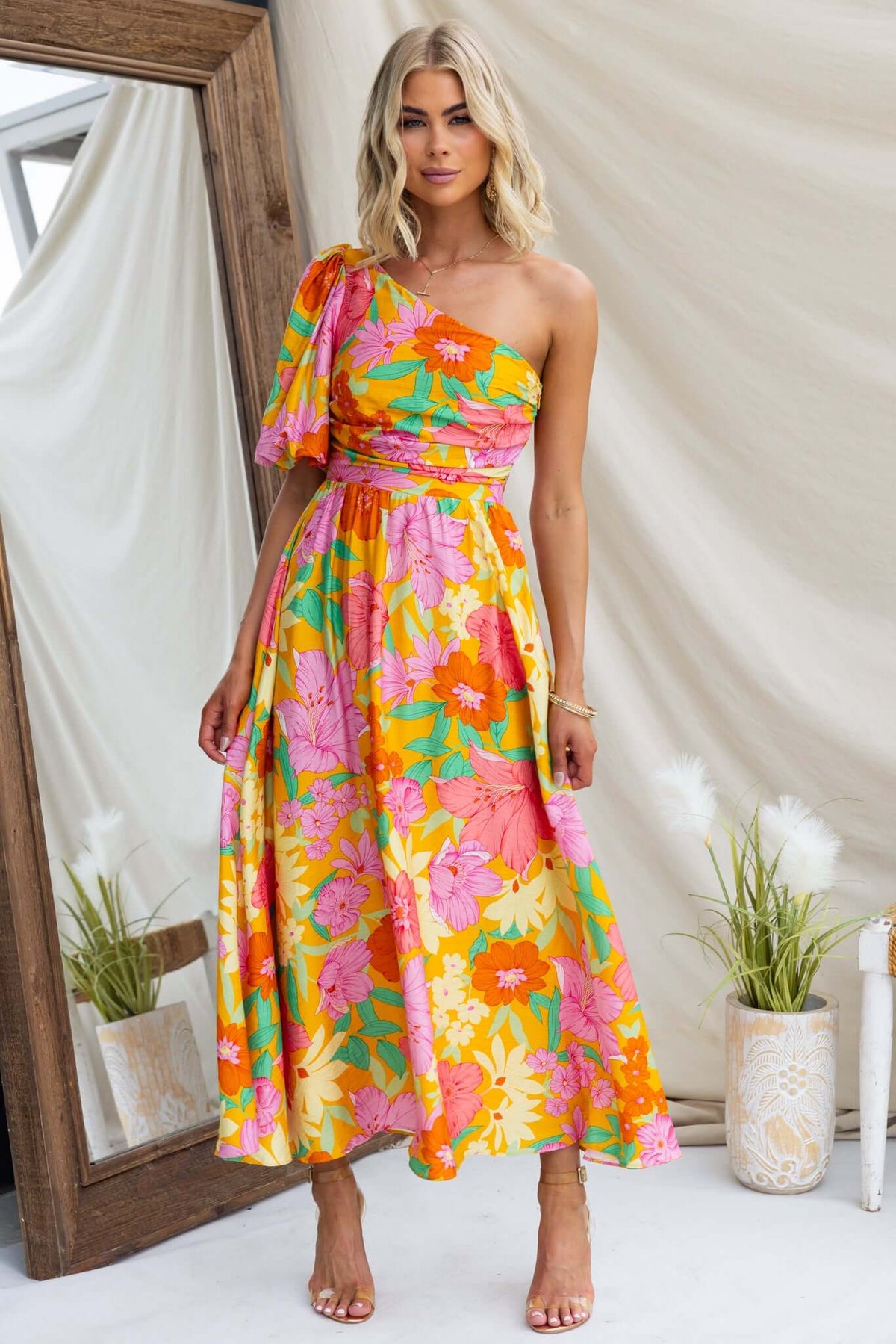Model wearing Woran Midi Dress with floral print, one-shoulder neckline in vibrant colors, perfect for summer occasions.