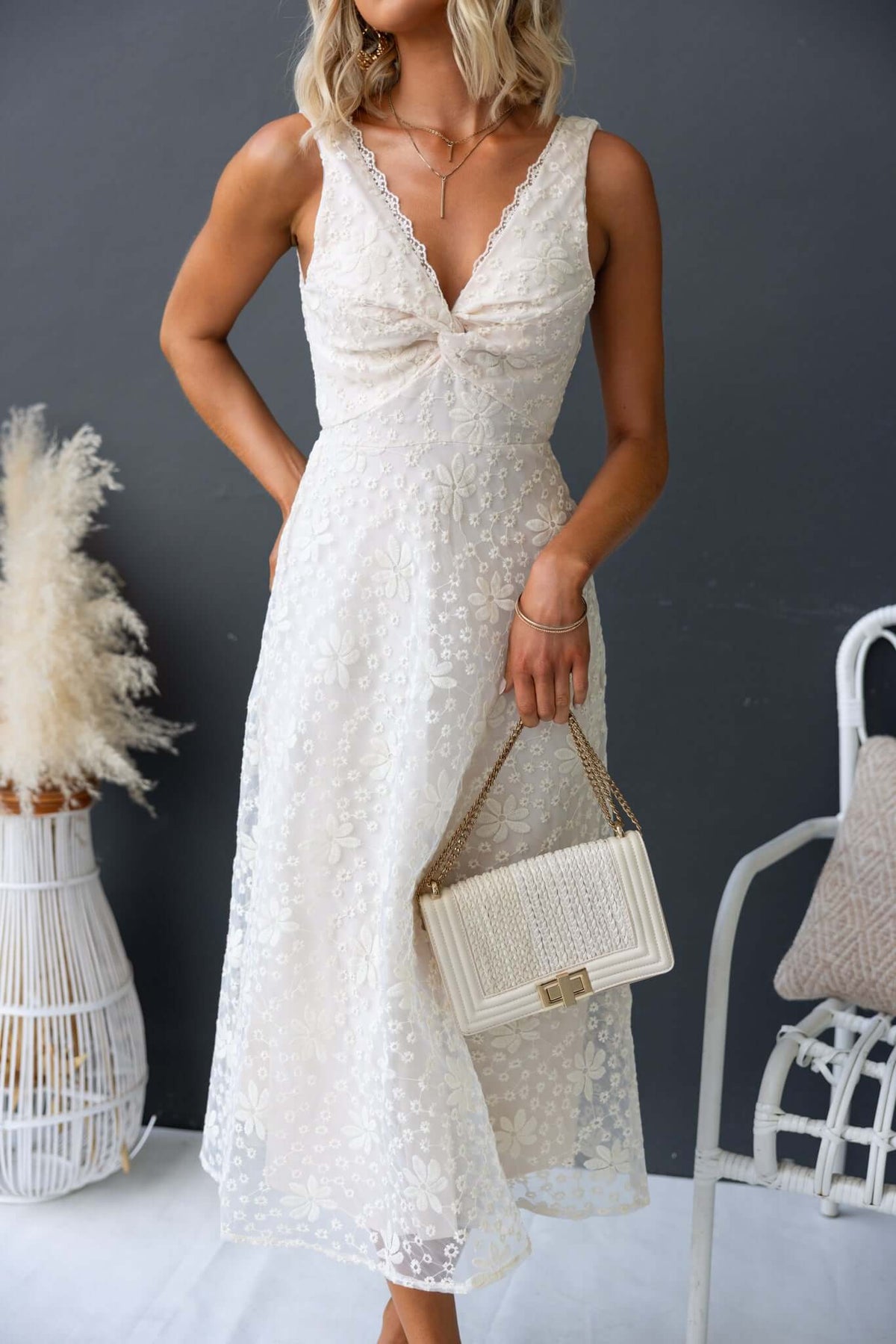Woman wearing Yakima Midi Dress with twist bust and lace detailing, holding a stylish handbag.