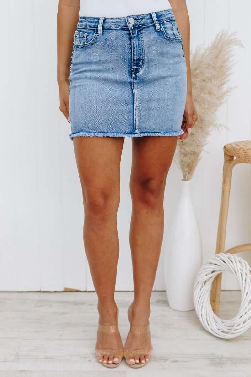 Model wearing Nice For What distressed denim skirt with raw hemline and pockets, showcasing stylish casual look.