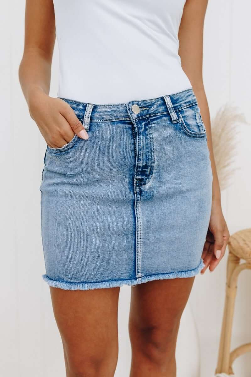 Nice For What Skirt: Distressed denim mini skirt with pockets and a raw hemline, featuring a standard fit and stretchy material.