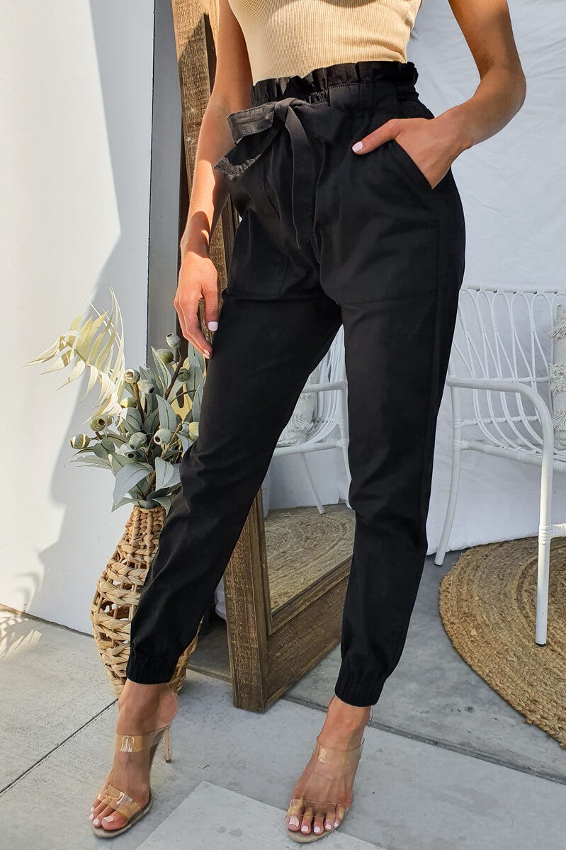 Zol Pants women's black trousers with elastic waistband, removable belt, and front pockets, styled with heels.