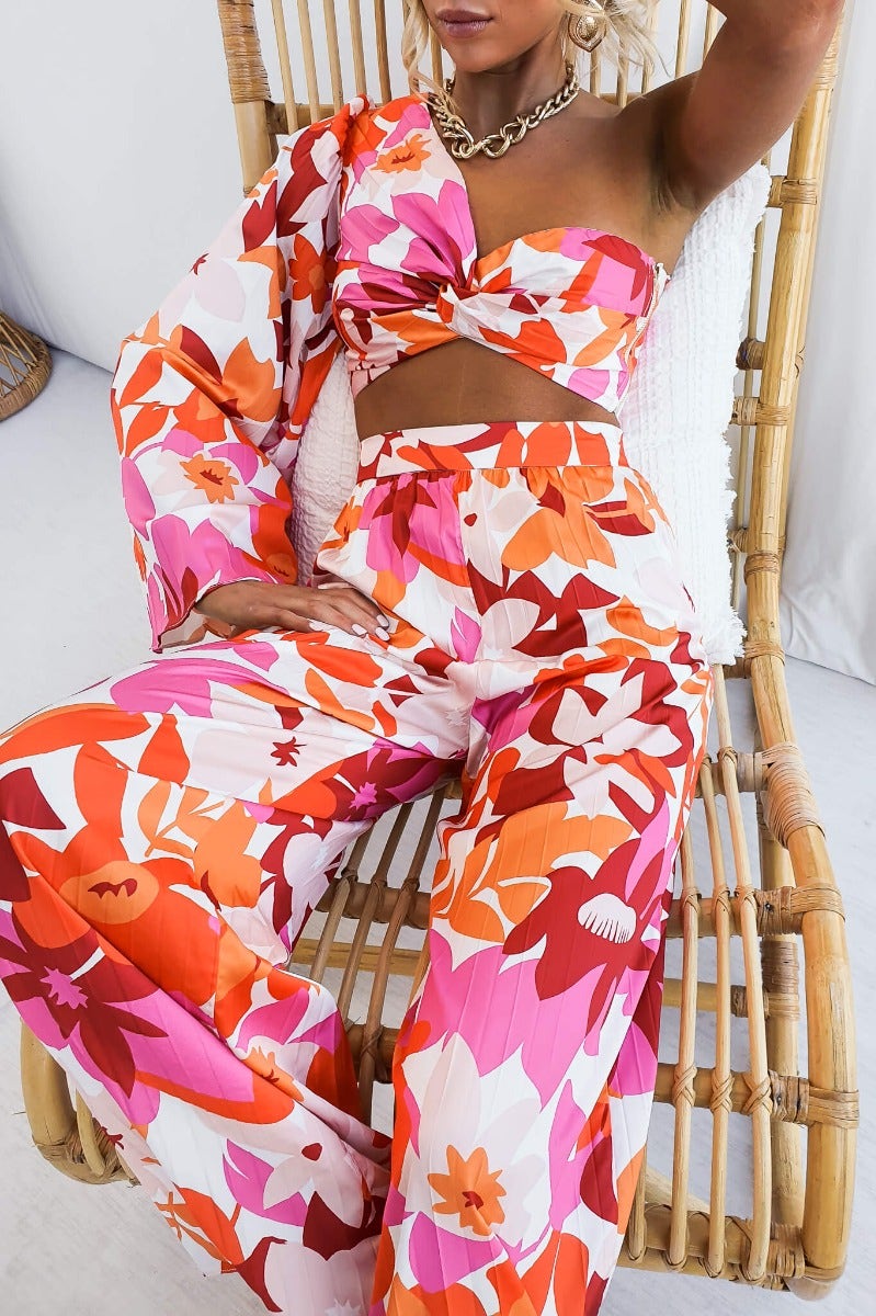 Model wearing Kira Set, a floral one-shoulder top and matching wide-leg pants in vibrant colors.