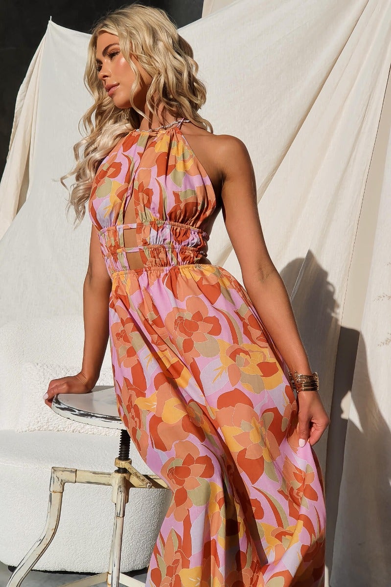 Model wearing Kariah Maxi Dress featuring colorful floral print, adjustable halter neckline, and cut-outs.