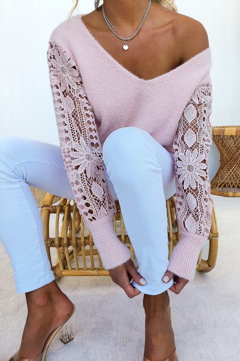 Fluffy pink v-neck jumper with lace sleeves, paired with light blue pants, styled casually.