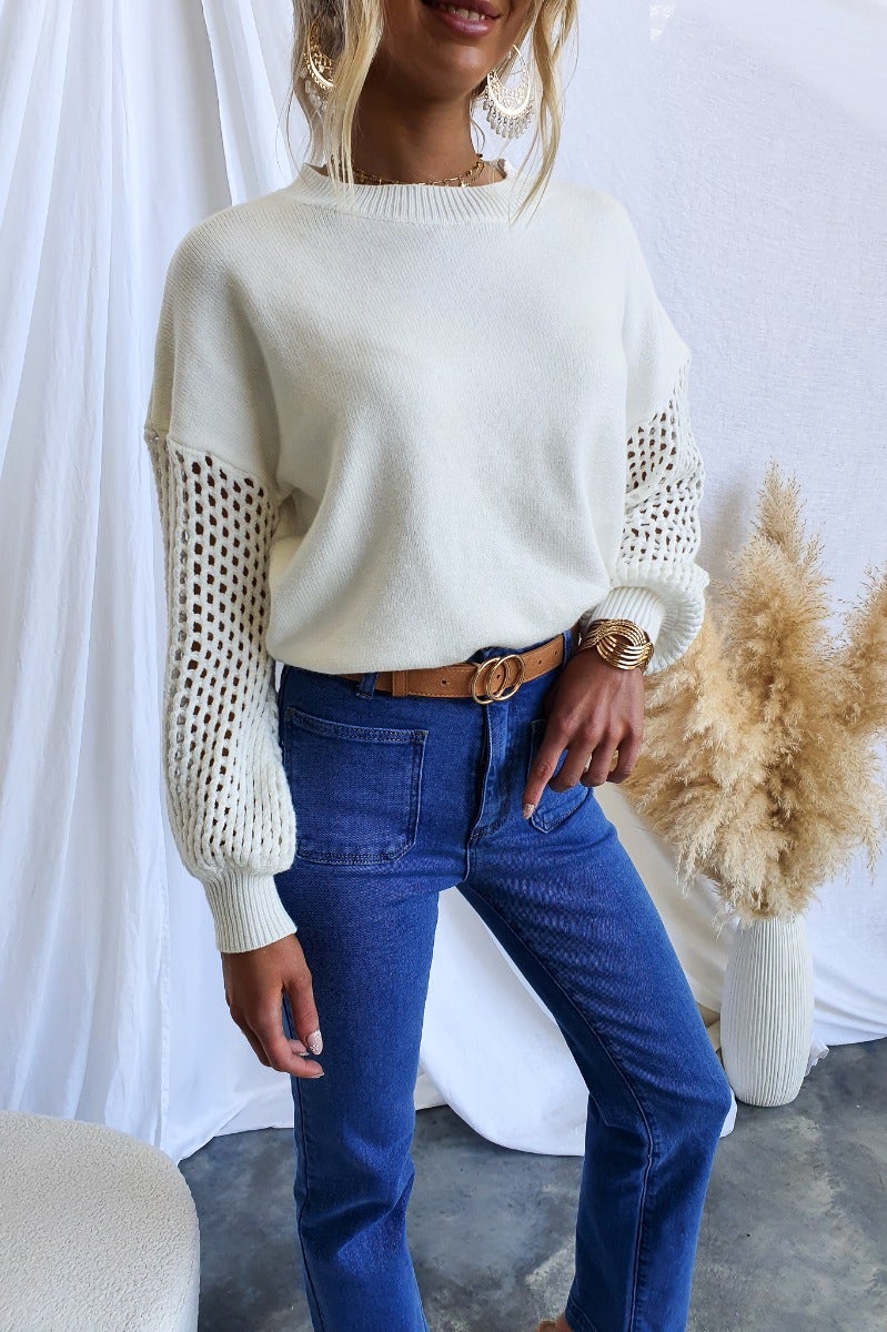 Verny Jumper featuring ribbed knit fabric, round neckline, and open weave sleeves styled with high-waisted jeans.