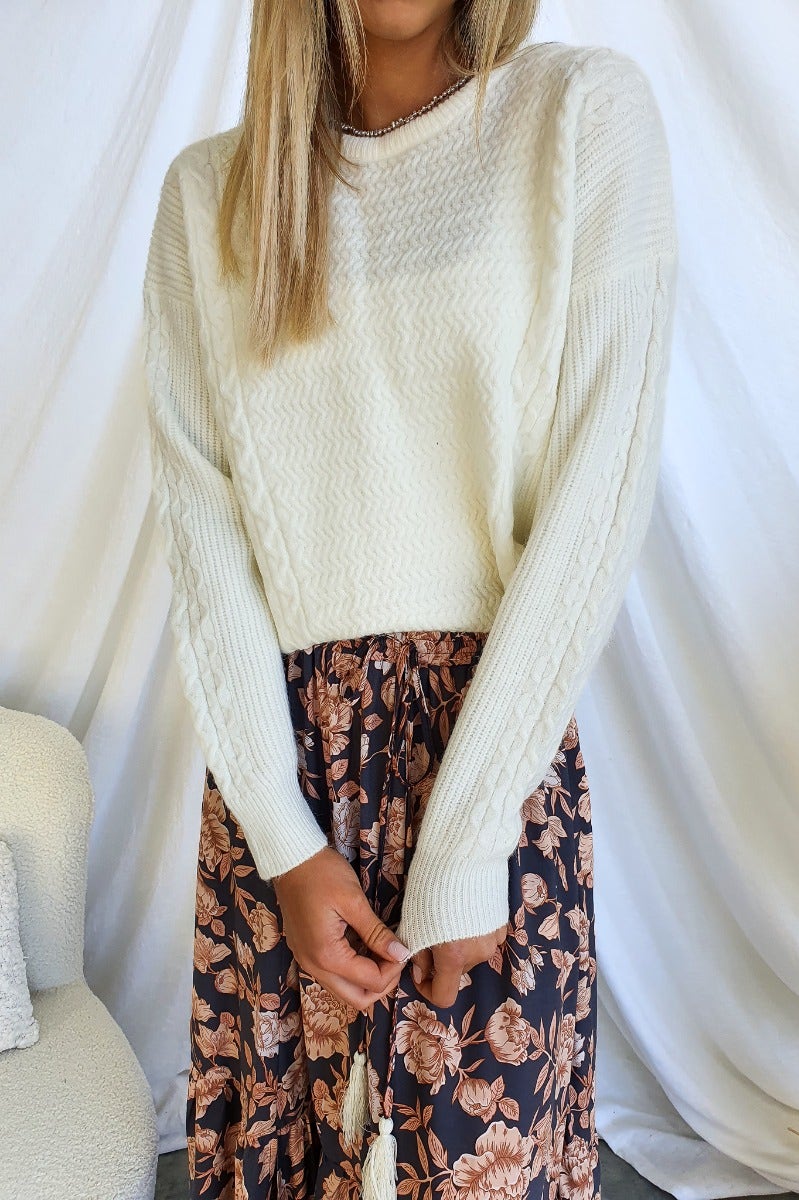 Model wearing a cream knit Gino Jumper paired with a floral skirt, showcasing a relaxed fit and round neckline.