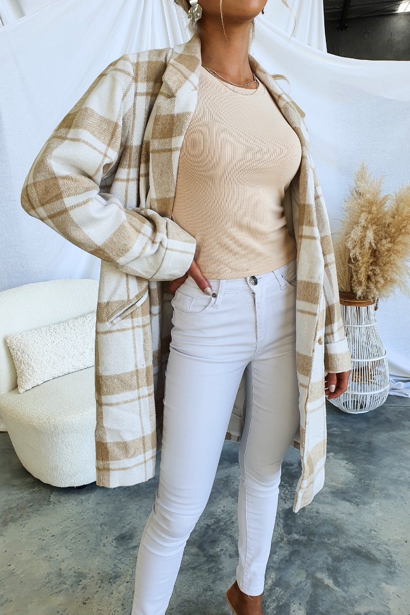 Woman wearing a plaid print Sabine coat with a beige top and white jeans, showcasing a stylish casual outfit.