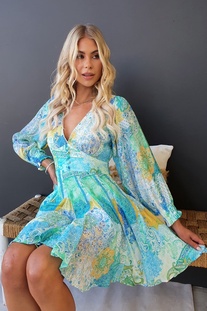 Model wearing the Forever Glow Dress, a multi-colour printed dress with a V-neckline and long sleeves.