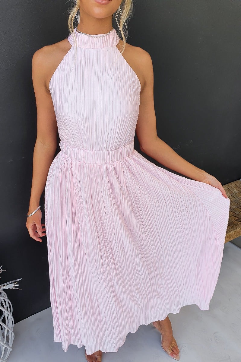Tyran Maxi Dress featuring accordion pleats, high tie neckline, and elastic waistband in soft pink color.
