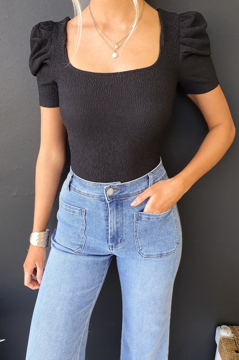 Black textured Darby bodysuit with cap sleeves, paired with denim jeans, showcasing a stylish look.