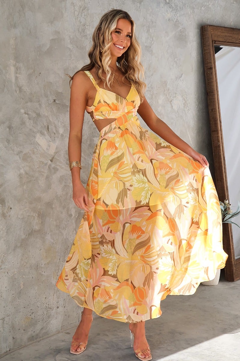 Model wearing floral print Blancia maxi dress with cut-out waist and tie-back detail, perfect for summer occasions.